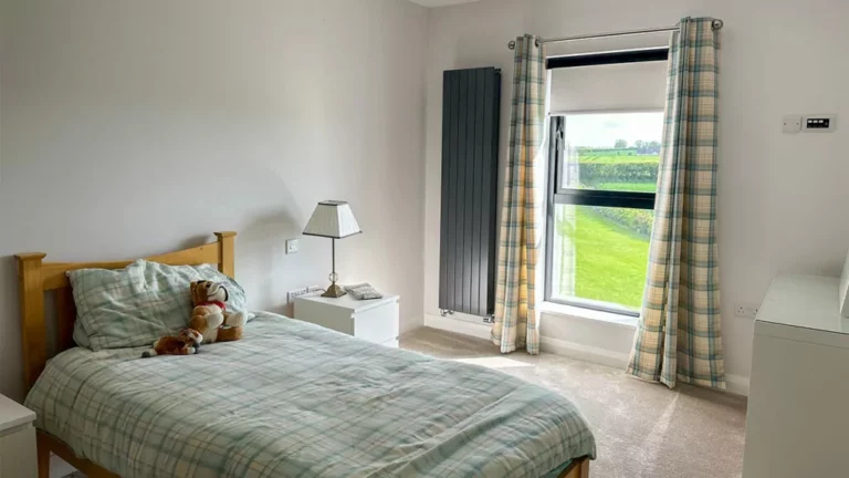 Bedroom with bed, curtains and made-to-measure roller blind fitted at the window