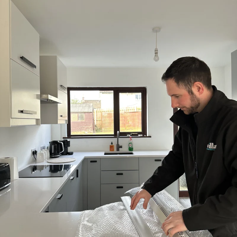 Village Blinds fitter preparing made-to-measure components carefully inside a customer kitchen