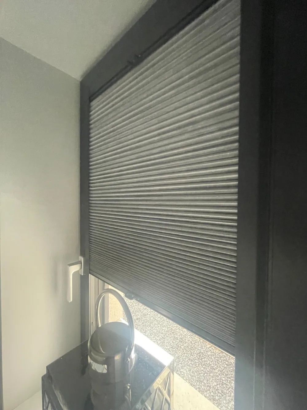 Real Village installation of a grey cellular Perfect Fit blind held within a dark window frame
