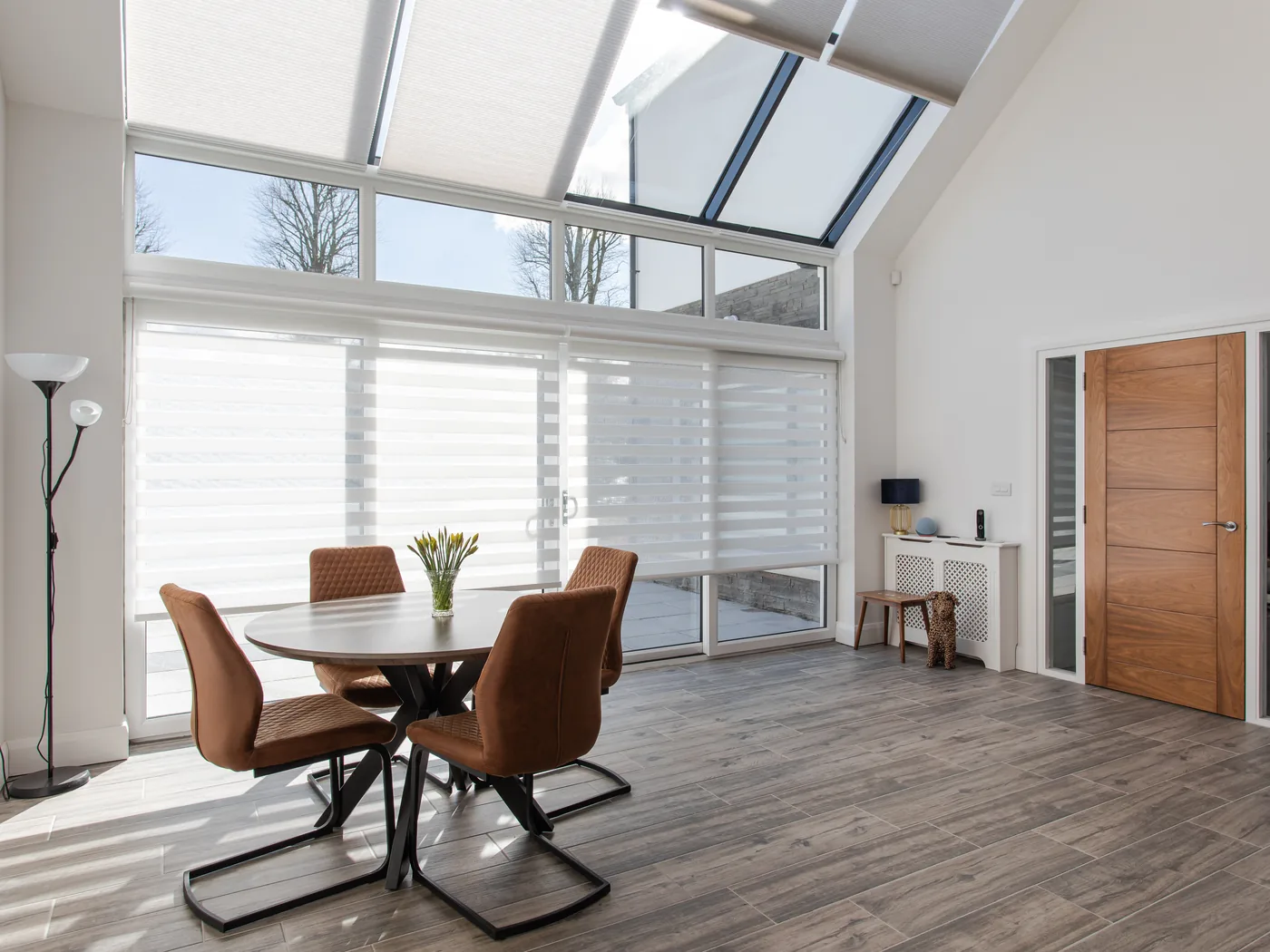 White cellular roof window blinds fitted across a bank of sloping glazed panels above a bright open-plan dining area
