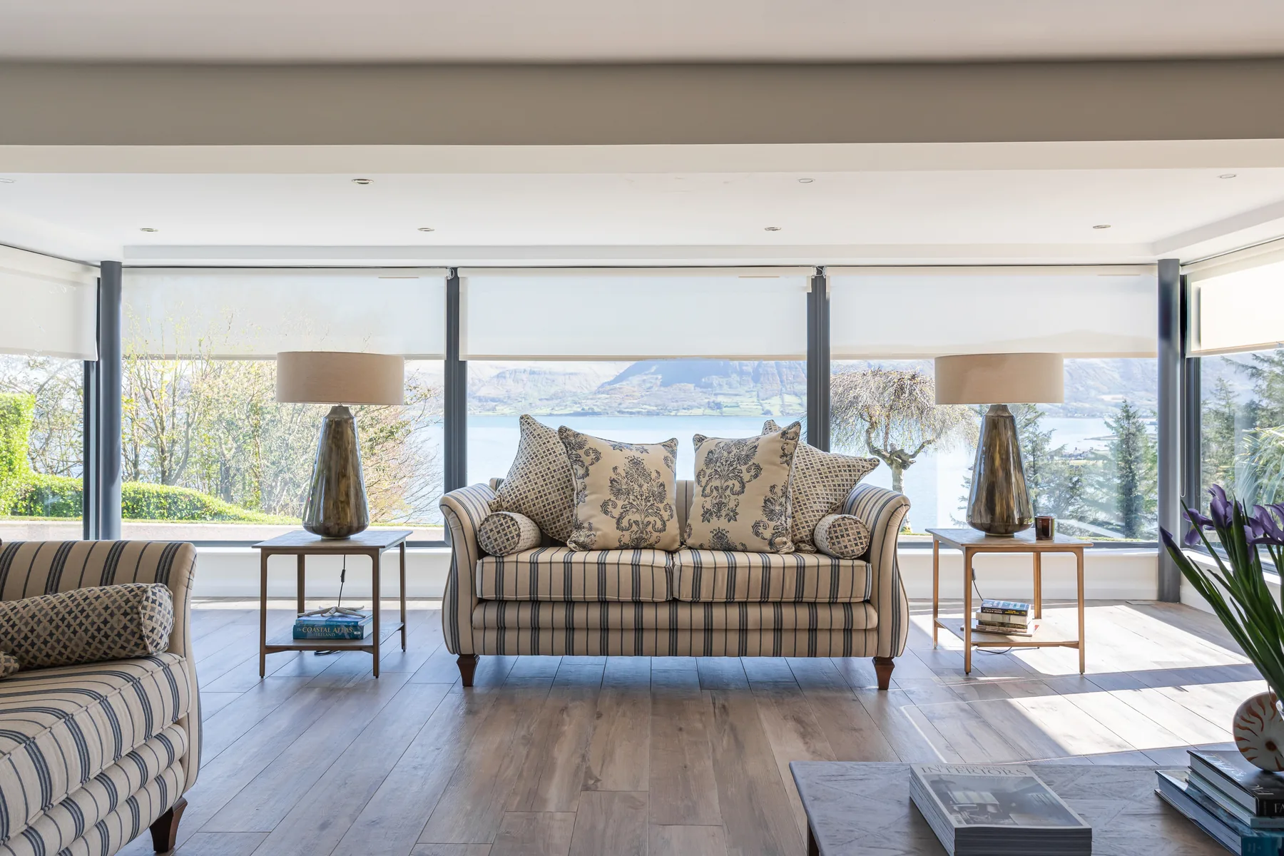 Neutral Roller blinds fitted across bright living-room glazing