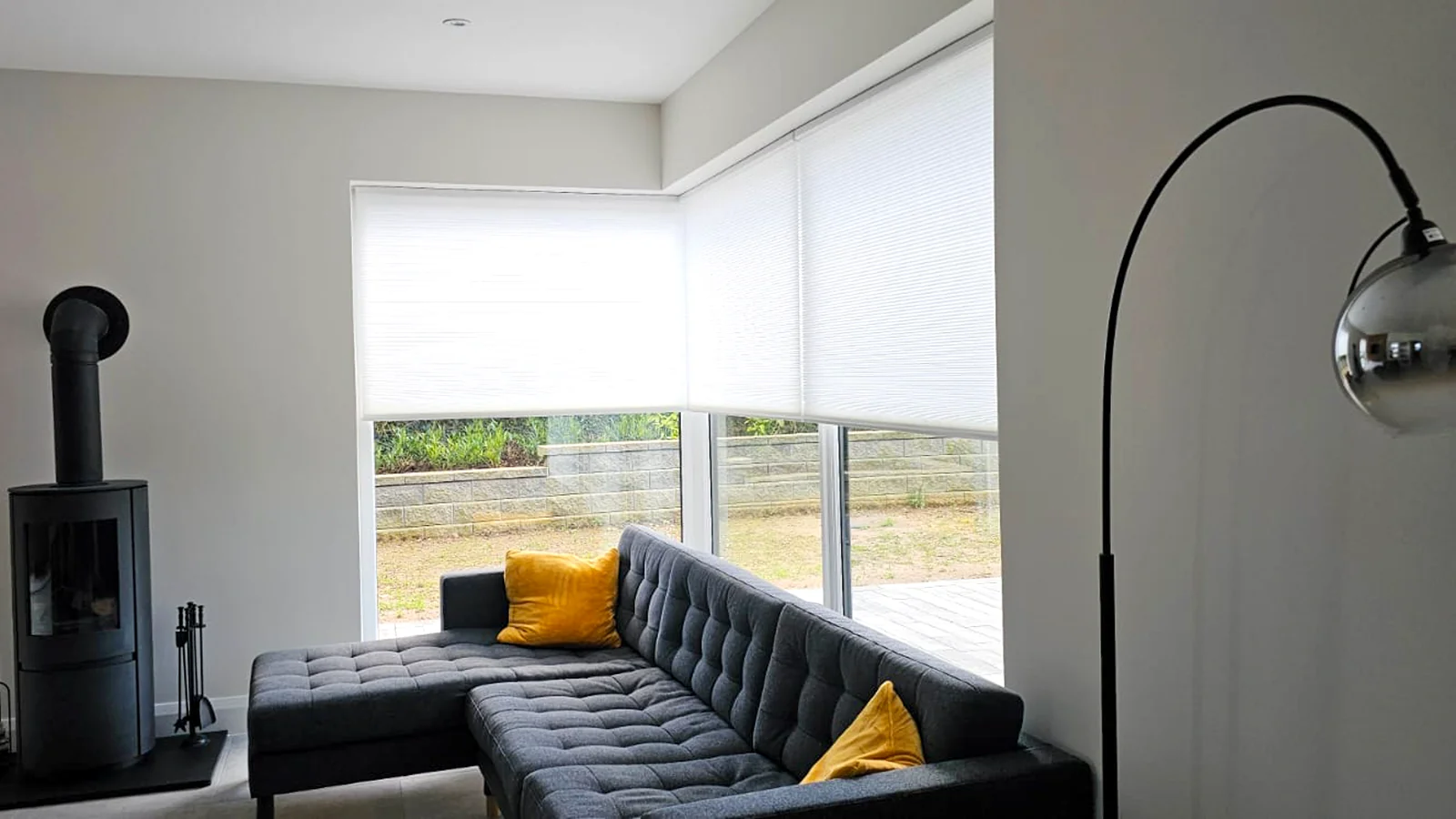 White cellular blinds fitted around a bright living-room corner window