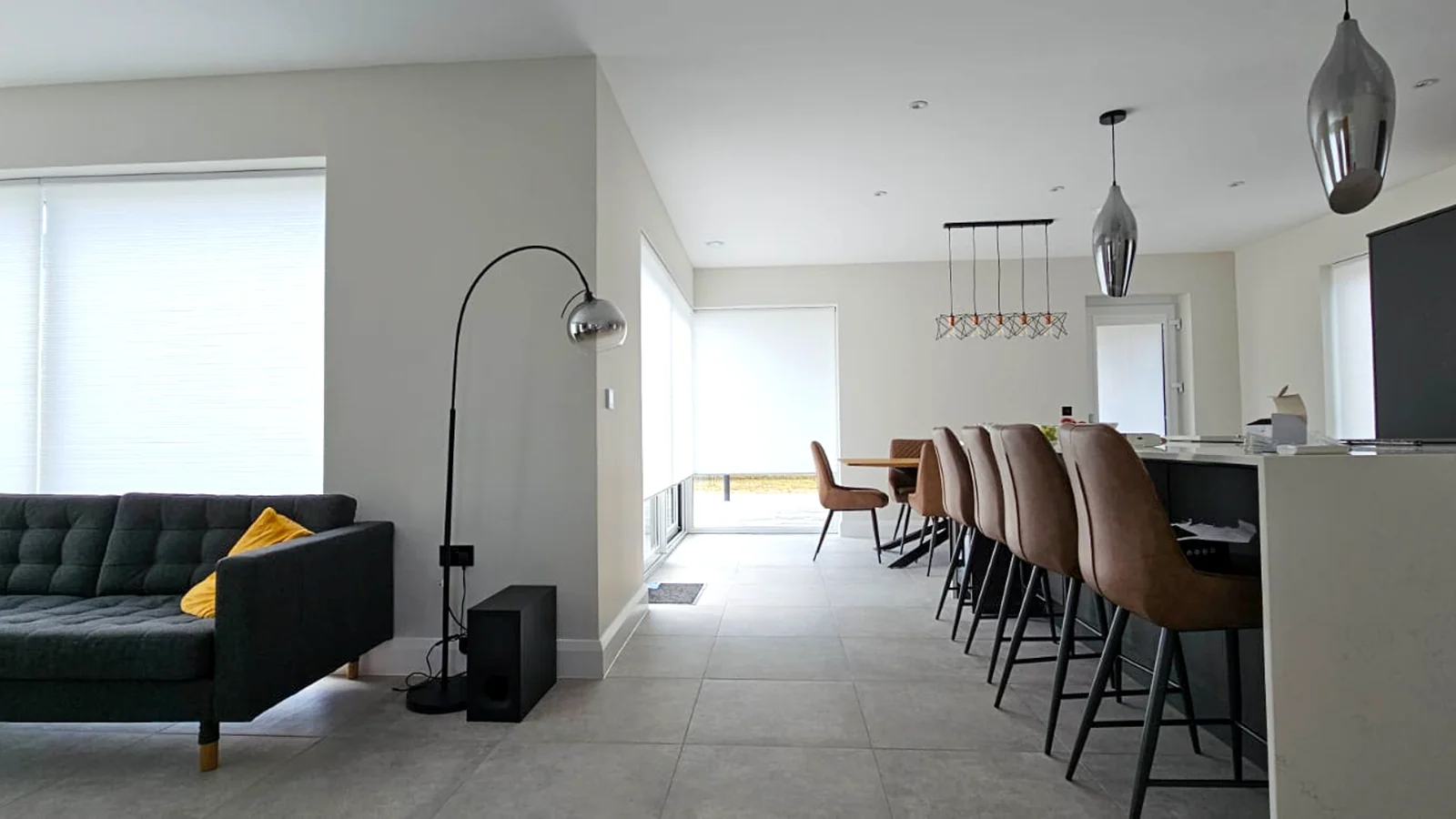 White cellular blinds fitted across large windows in a modern open-plan home