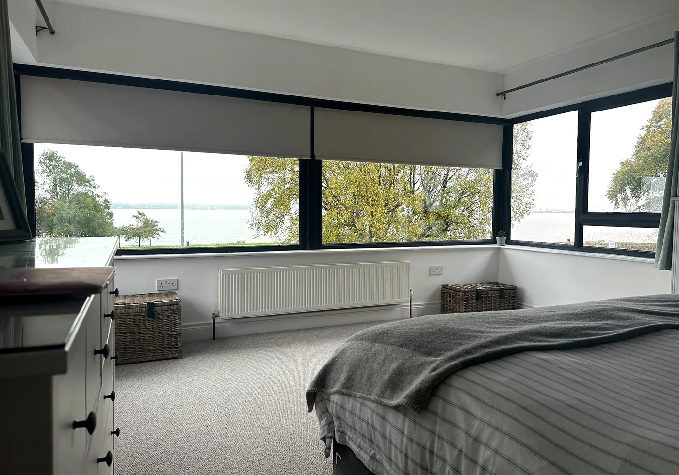 Motorised roller blinds fitted across wide black-framed windows