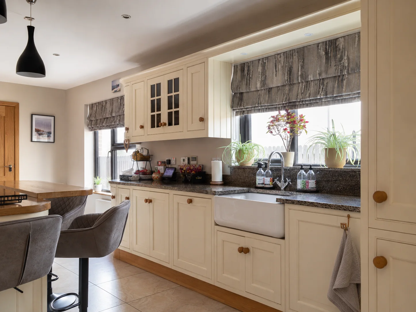 Patterned Roman blinds fitted in a cream kitchen