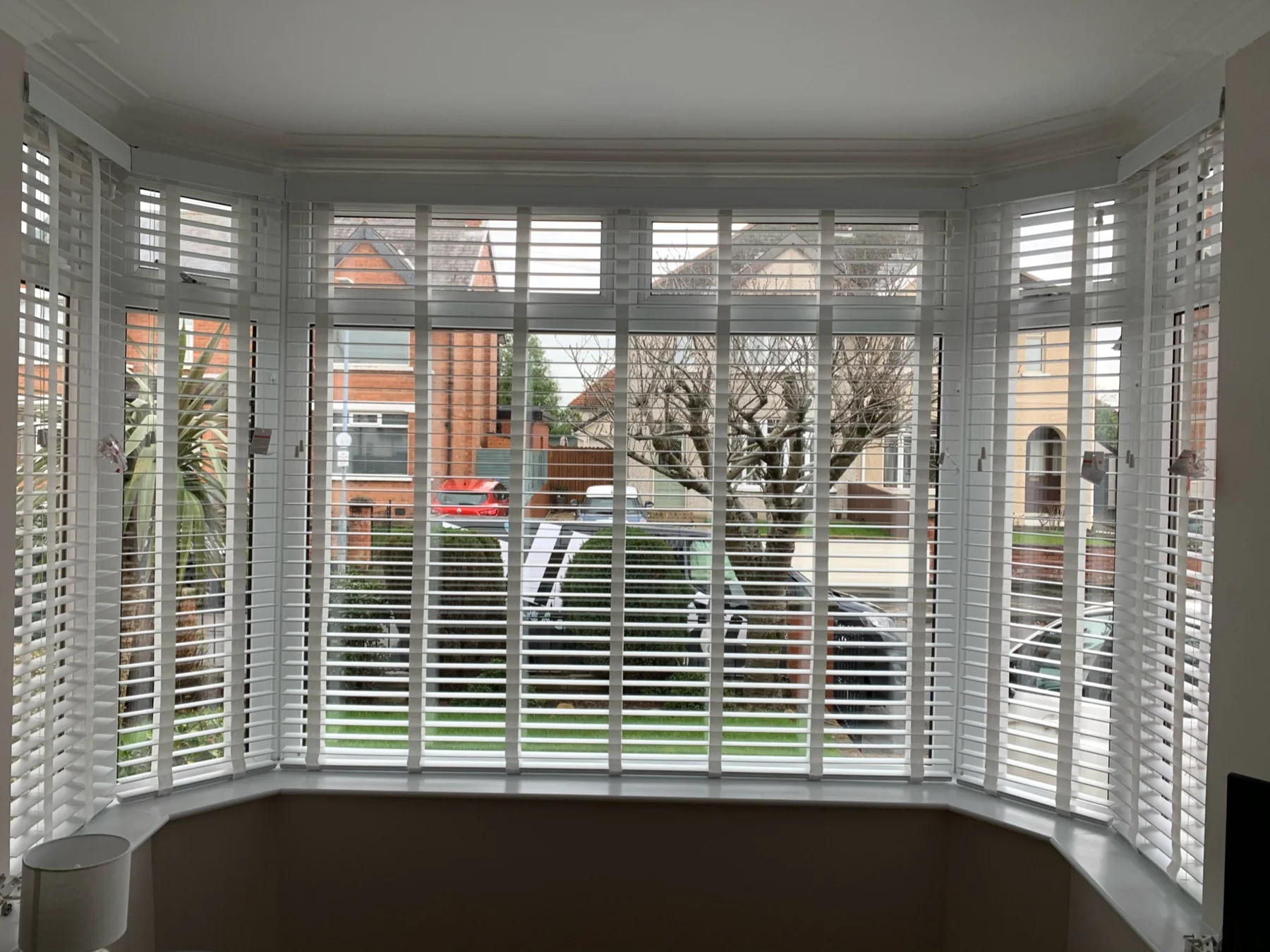 White wooden Venetian blinds fitted around a bay window