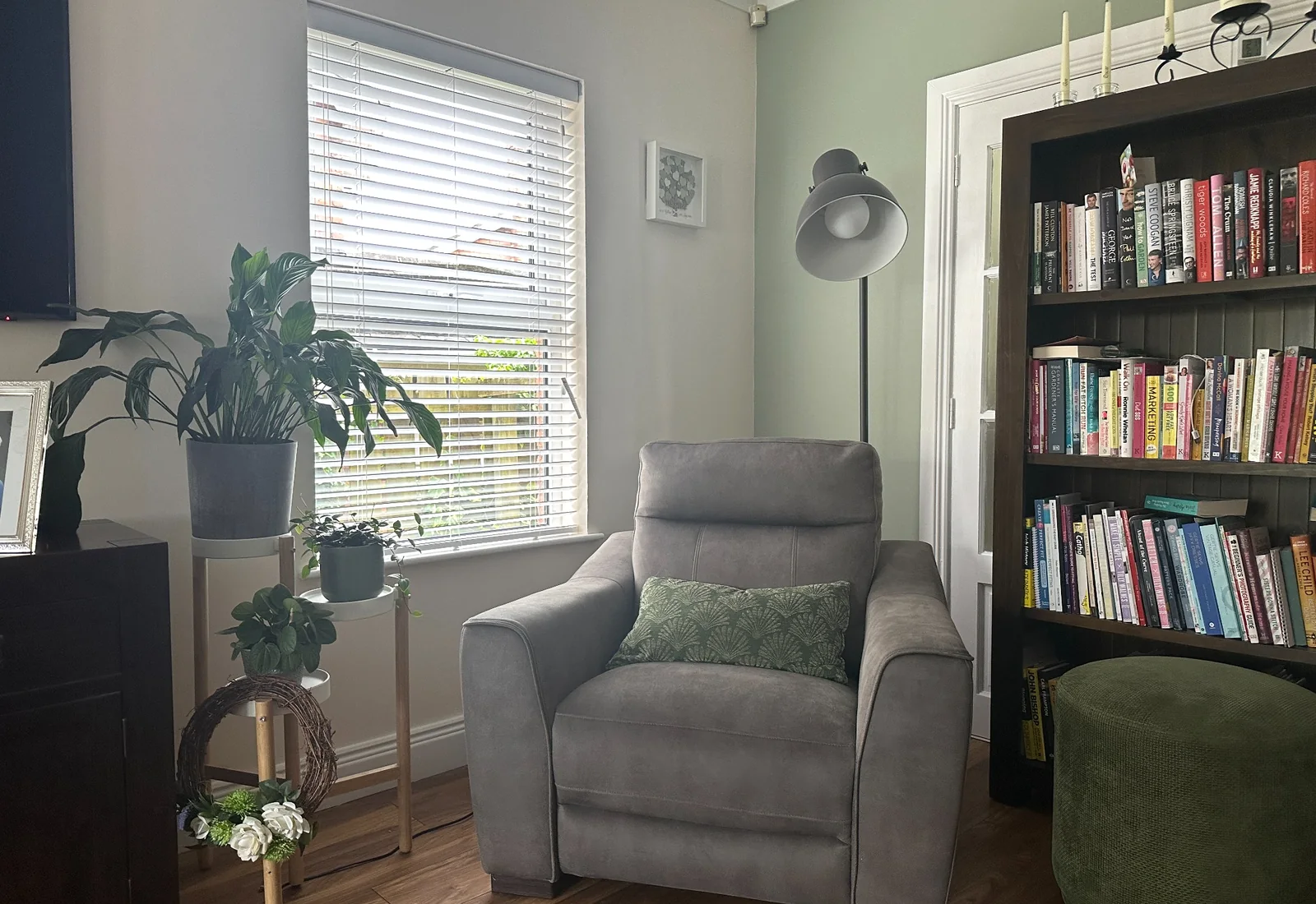 White wooden blind fitted in a living room beside a reading chair