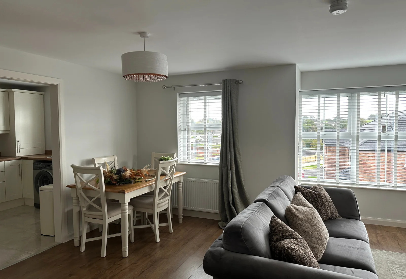 White wooden blinds fitted across an open-plan living and dining room