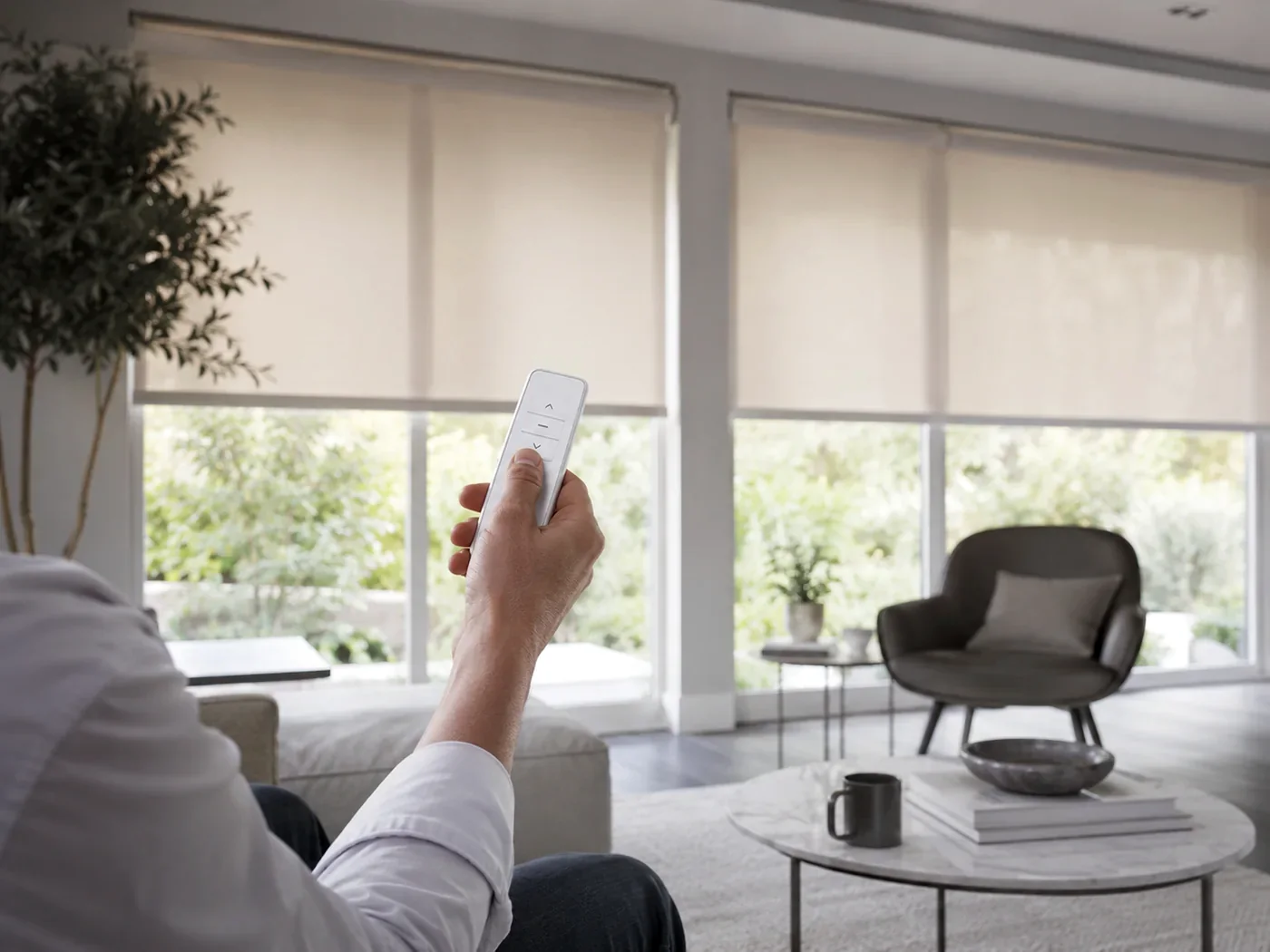 Remote control being used to operate several motorised roller blinds