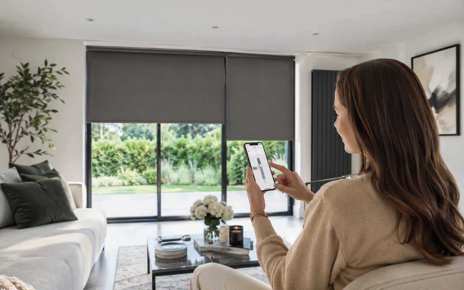 Homeowner using a smartphone to control motorised roller blinds in a modern living room