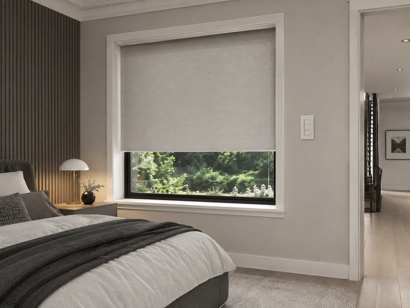 Motorised roller blind in a bedroom with a wall-mounted blind control beside the window