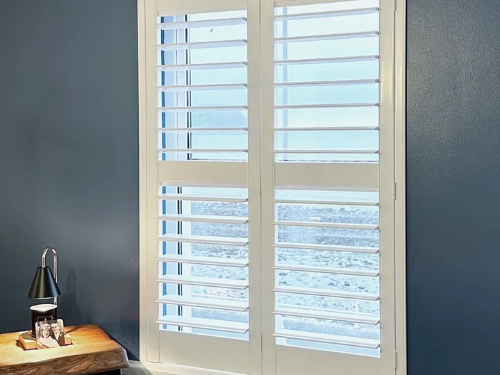 Closer interior view of white Lumin shutters above a dining table