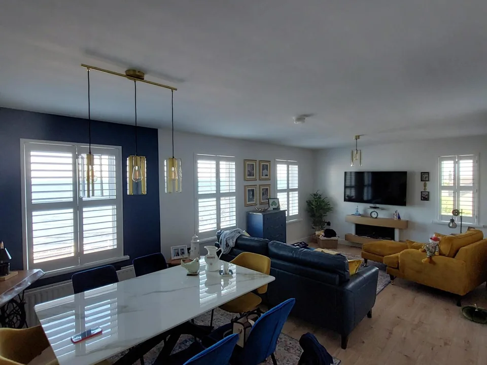 Open-plan living and dining room with white Lumin shutters fitted across multiple windows