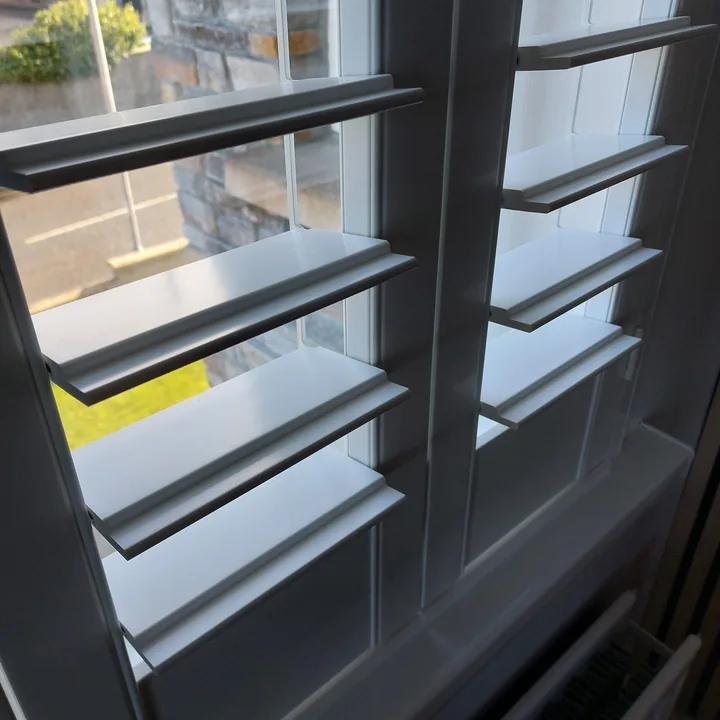 Close-up side view of white Lumin shutter louvres showing the broad louvre faces and stepped profiled edges
