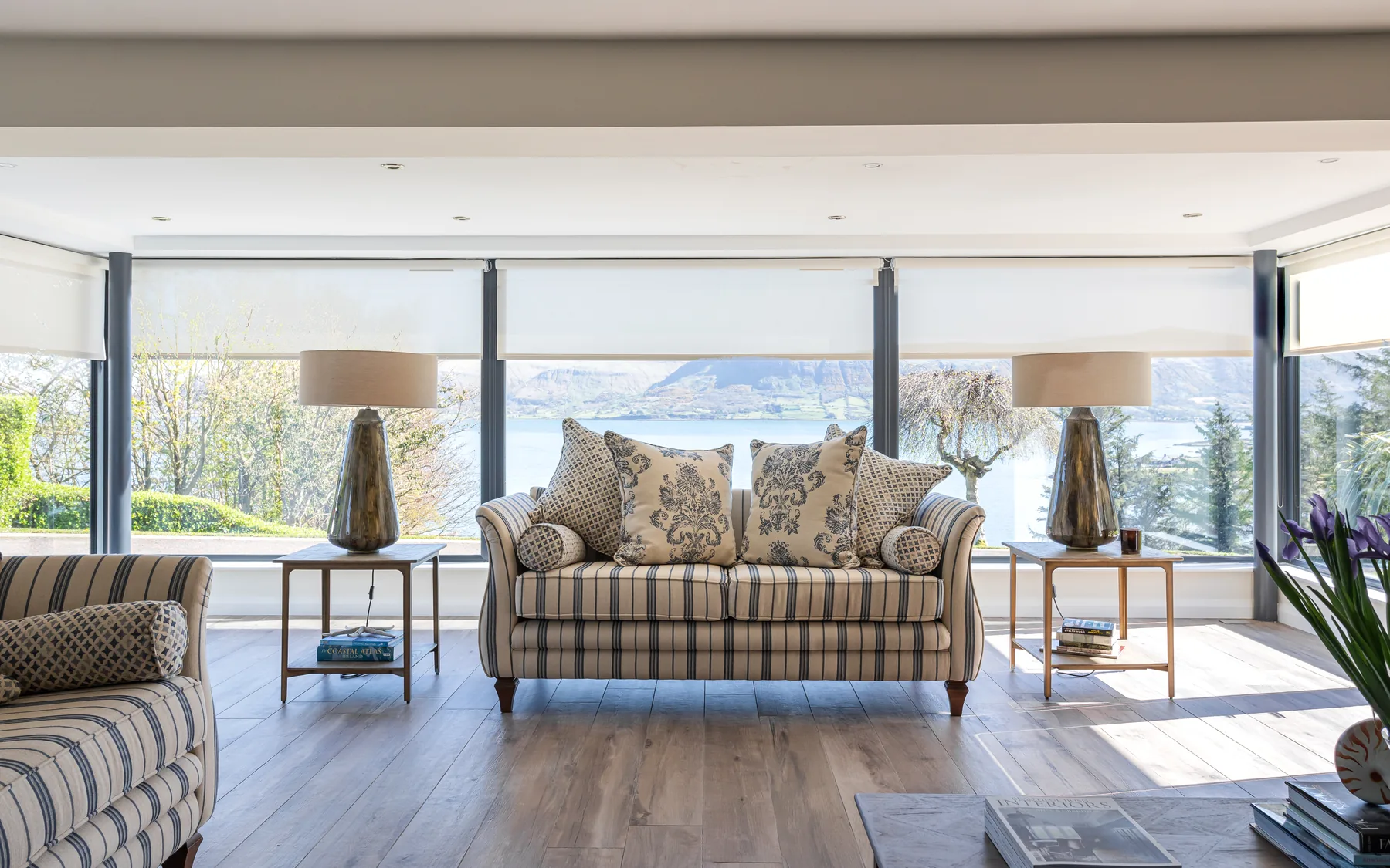 Motorised roller blinds across wide windows in a bright Northern Ireland living room