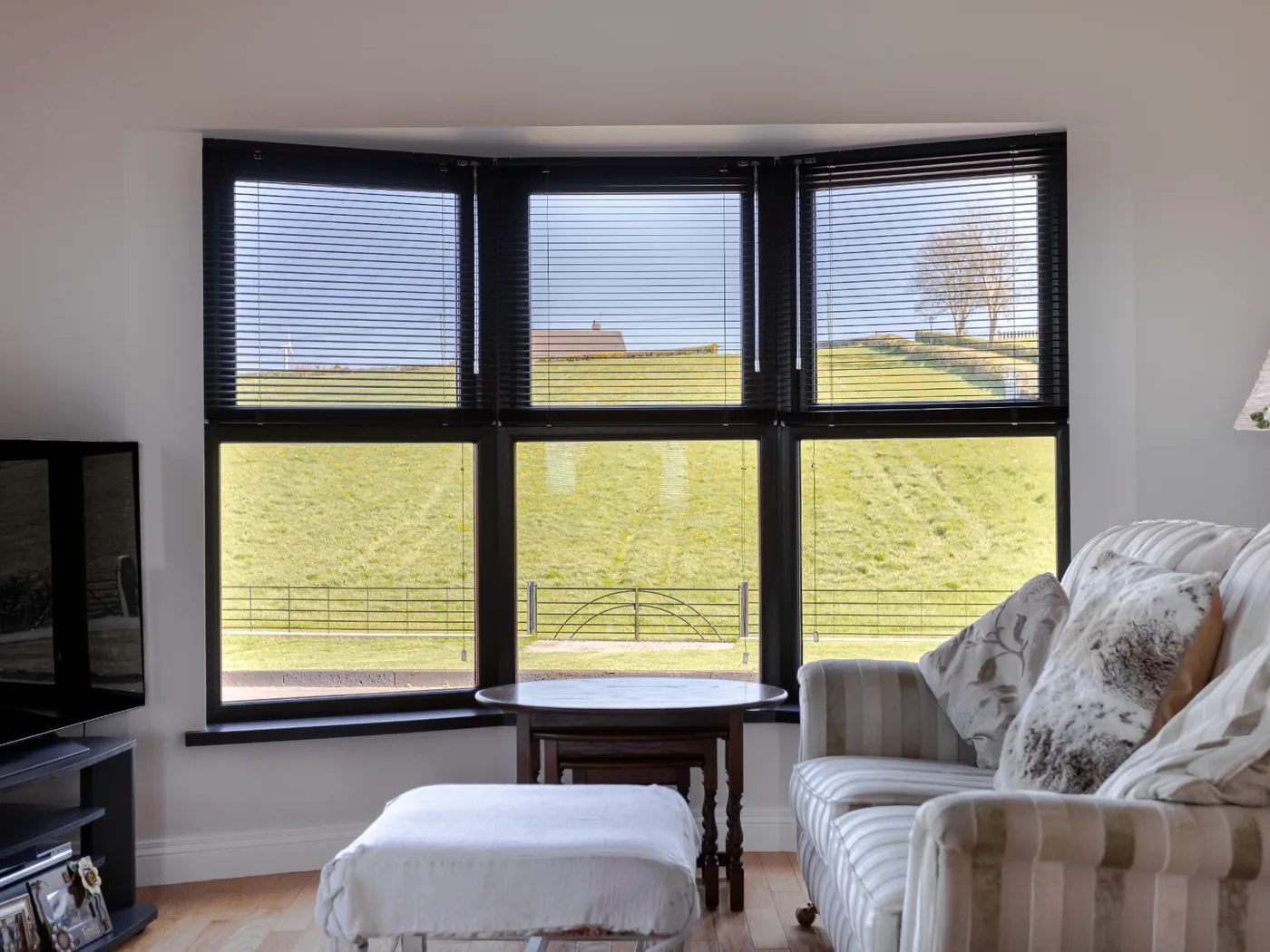 Dark Venetian blinds fitted across a wide bay window