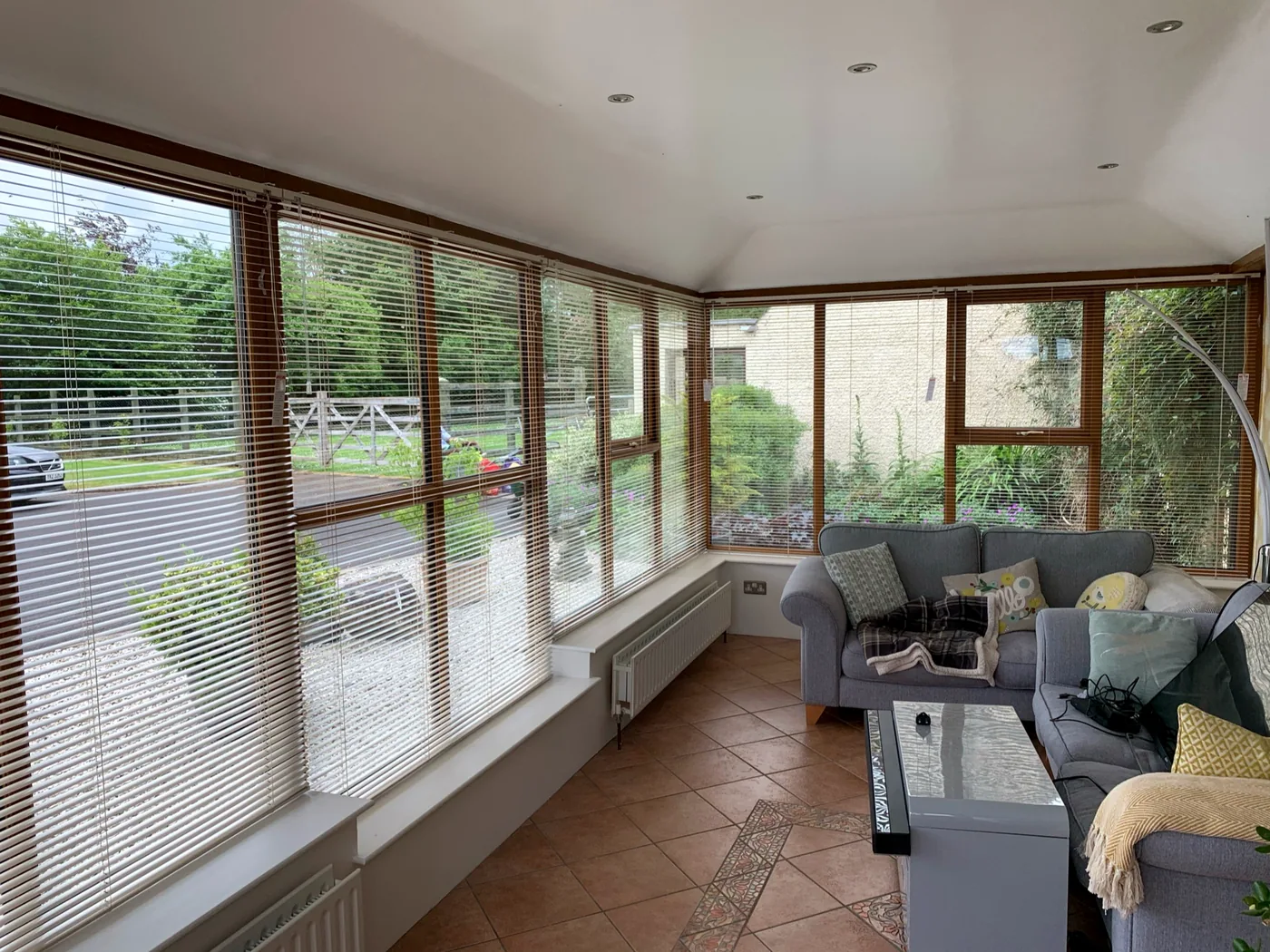 Warm-toned Venetian blinds across a bright conservatory