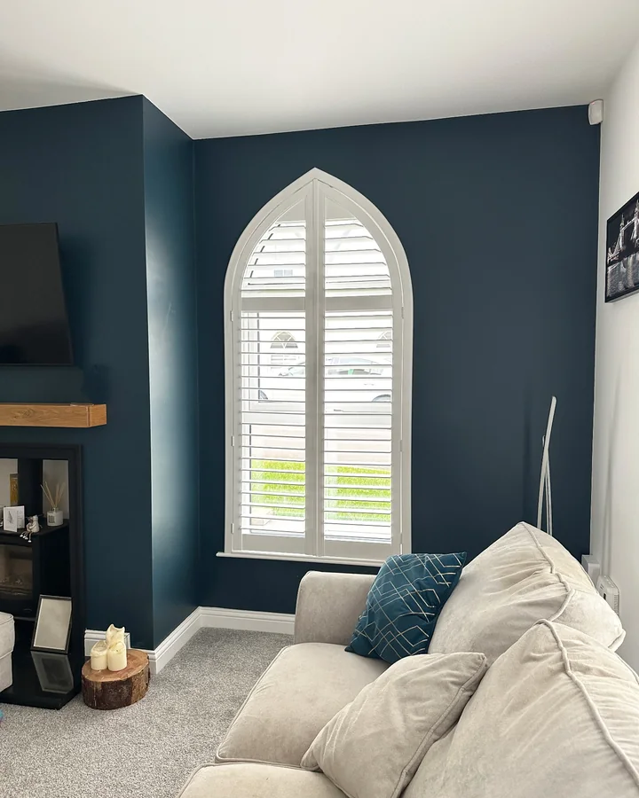 White Gothic arch plantation shutters fitted into a pointed feature window