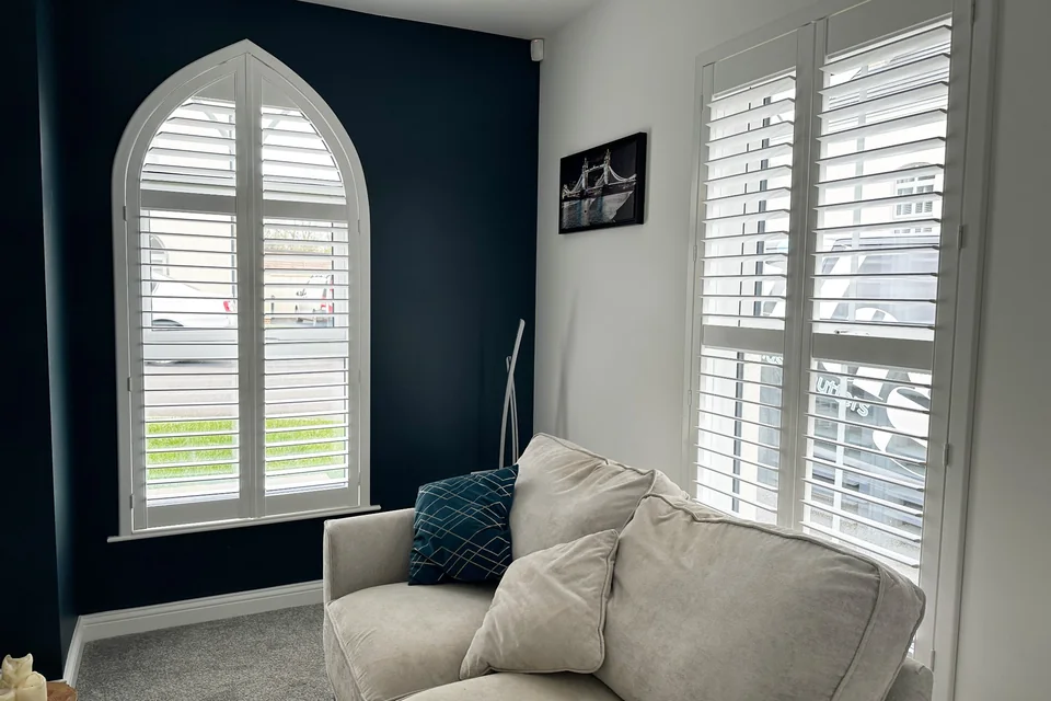 Gothic arch window fitted with made-to-measure white plantation shutters in a Northern Ireland living room