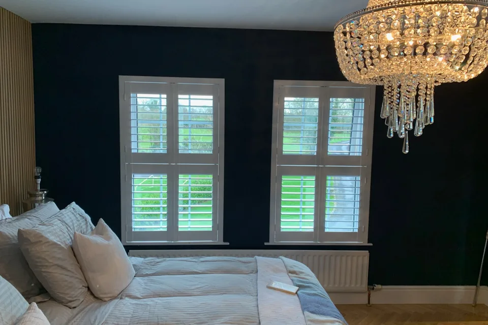 Bedroom with white Tier-on-Tier plantation shutters fitted to two windows