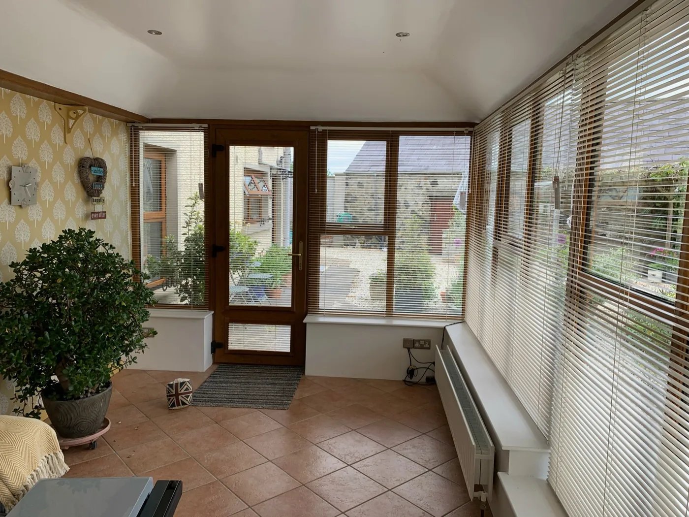 Pale Venetian blinds fitted across a bright garden-room entrance and surrounding windows