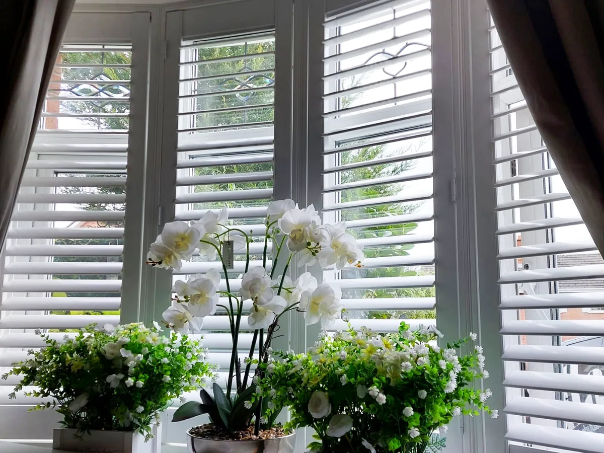 White plantation shutters fitted to a bay window in a living room