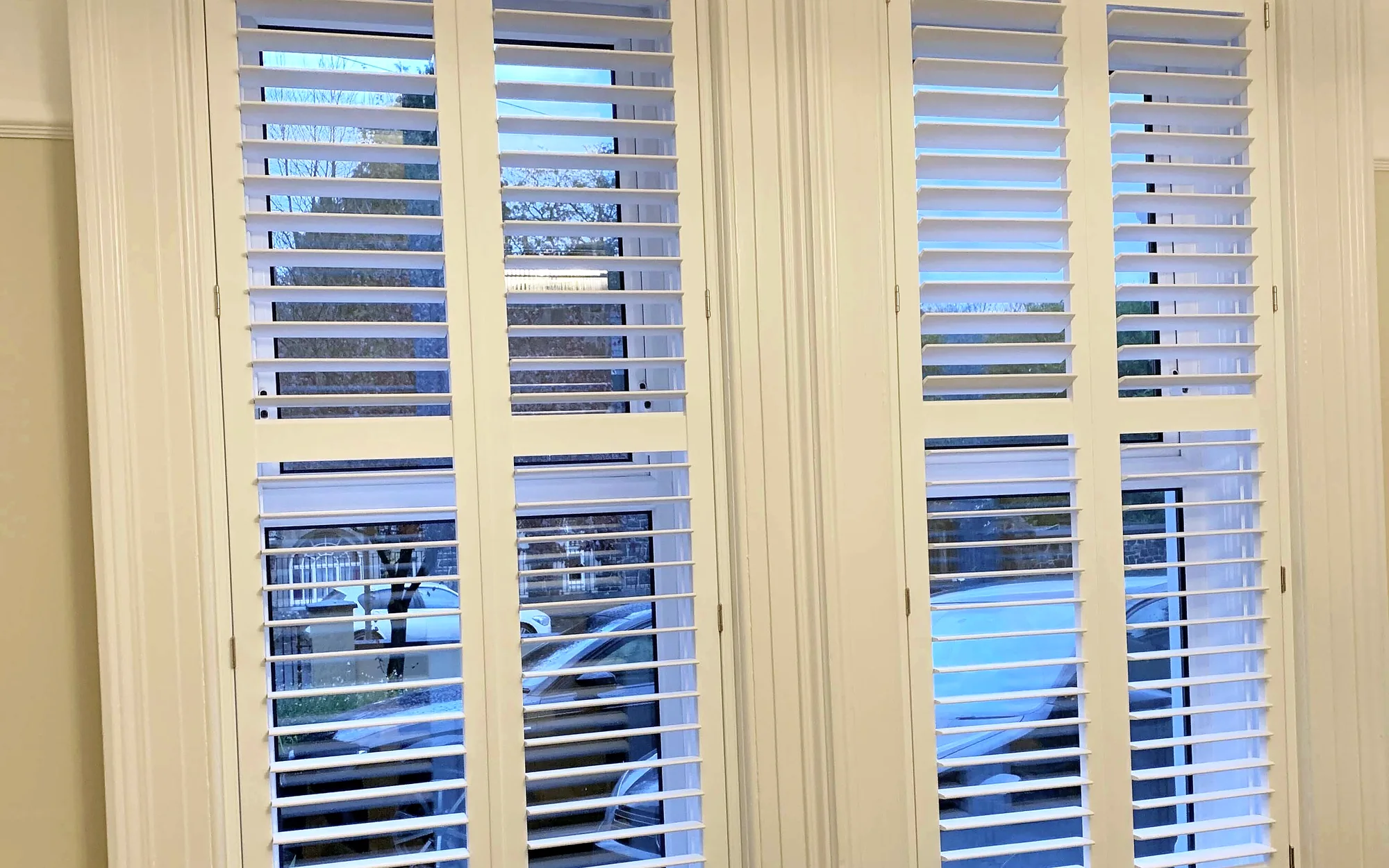 Full-height white plantation shutters fitted to tall windows in a Northern Ireland living room