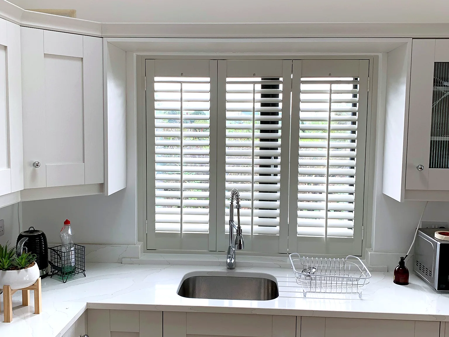 White plantation shutters fitted above a kitchen sink for privacy and adjustable daylight