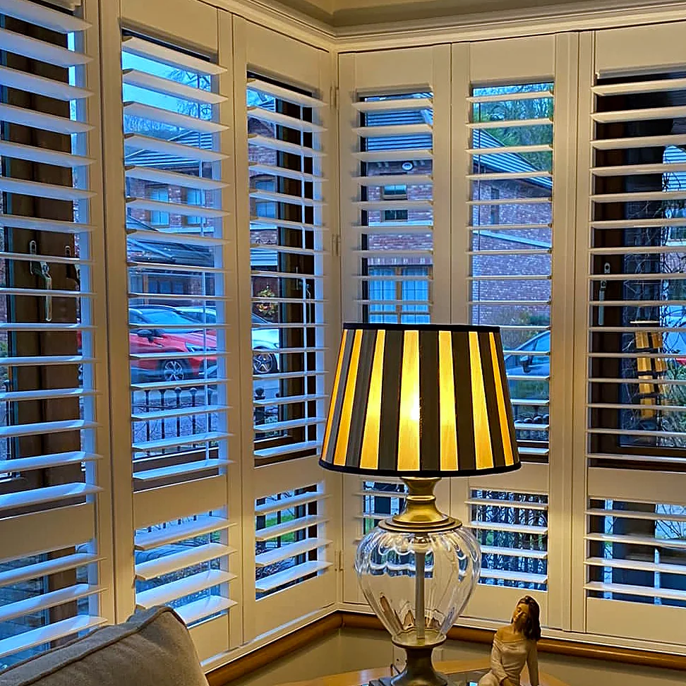 Close view of plantation shutter panels and adjustable louvres around a corner window