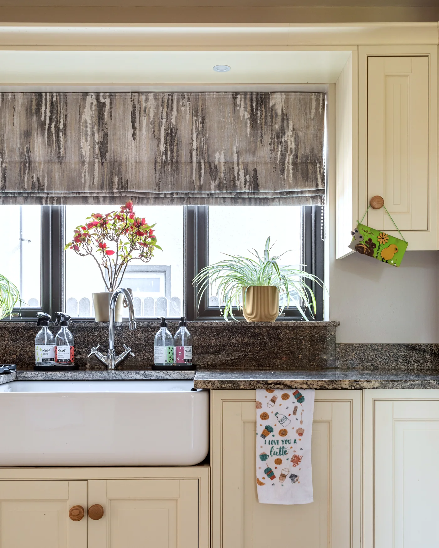 Patterned Roman blind fitted above a kitchen window with a soft decorative finish